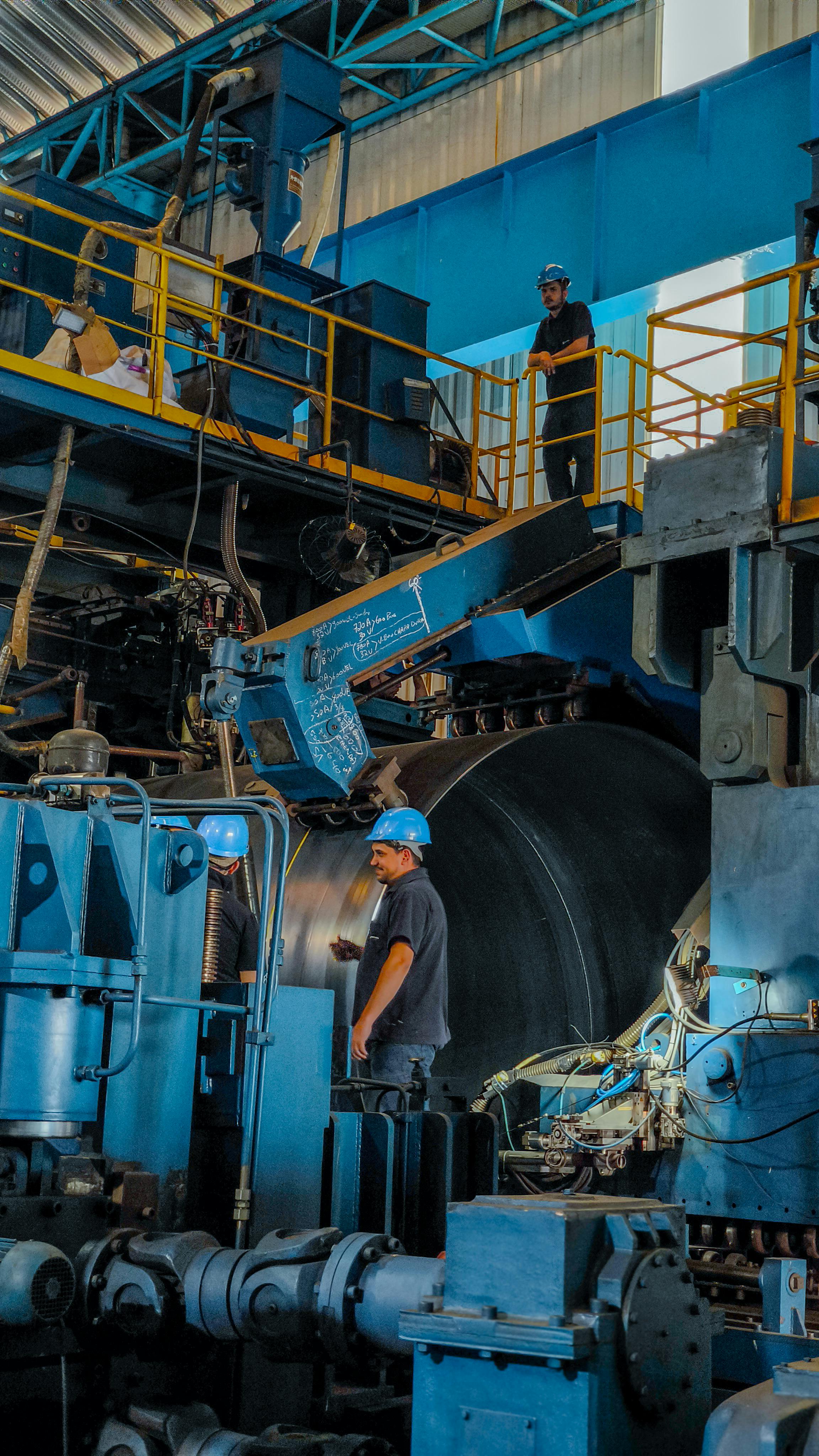 Workers operating machinery in a large industrial factory environment, showcasing industry and teamwork.