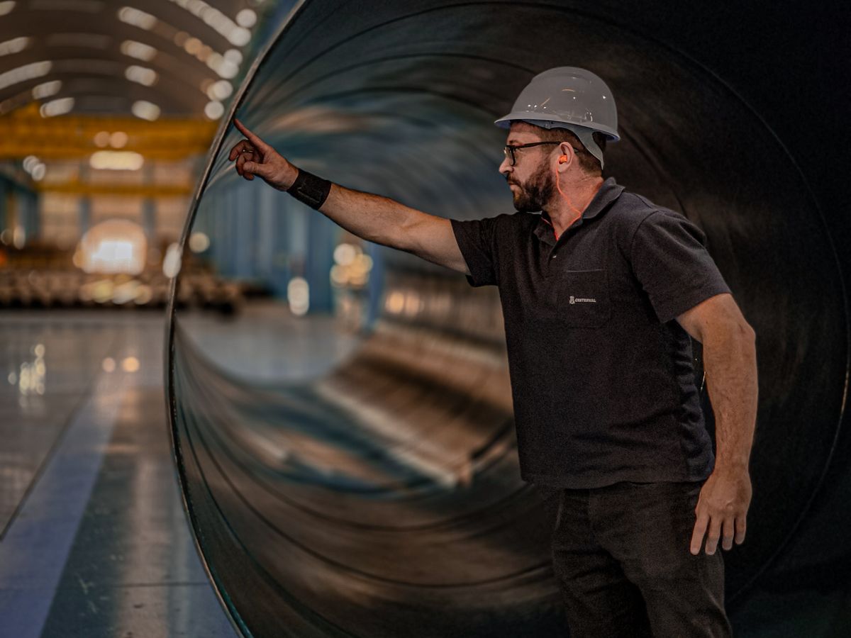 Worker in a helmet checking a large pipe.