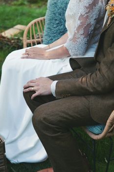Elegant close-up of a couple in wedding attire seated outdoors, showcasing beautiful lace details.