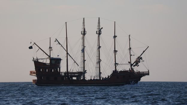 A grand pirate ship with full sails navigating the scenic ocean near Balneário Camboriú, Brazil.