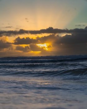 Stunning sunset with vibrant clouds over a calm ocean, creating a serene and dramatic view.
