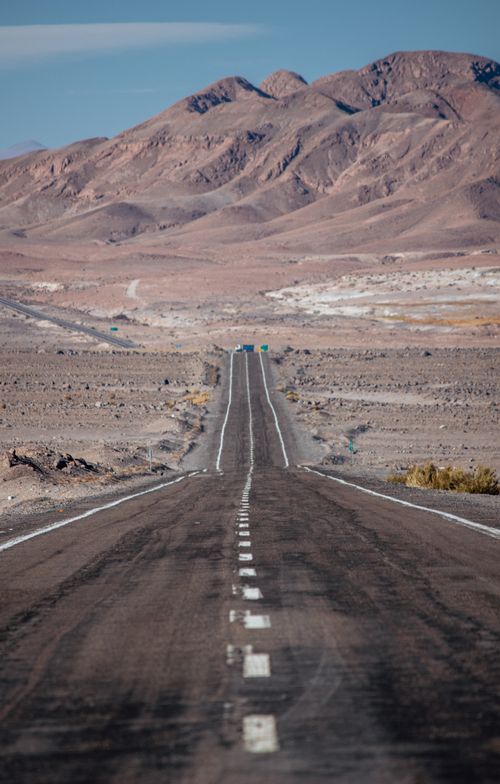 Free Long road stretching into distant mountains in a barren desert landscape. Ideal for adventure travel themes. Stock Photo