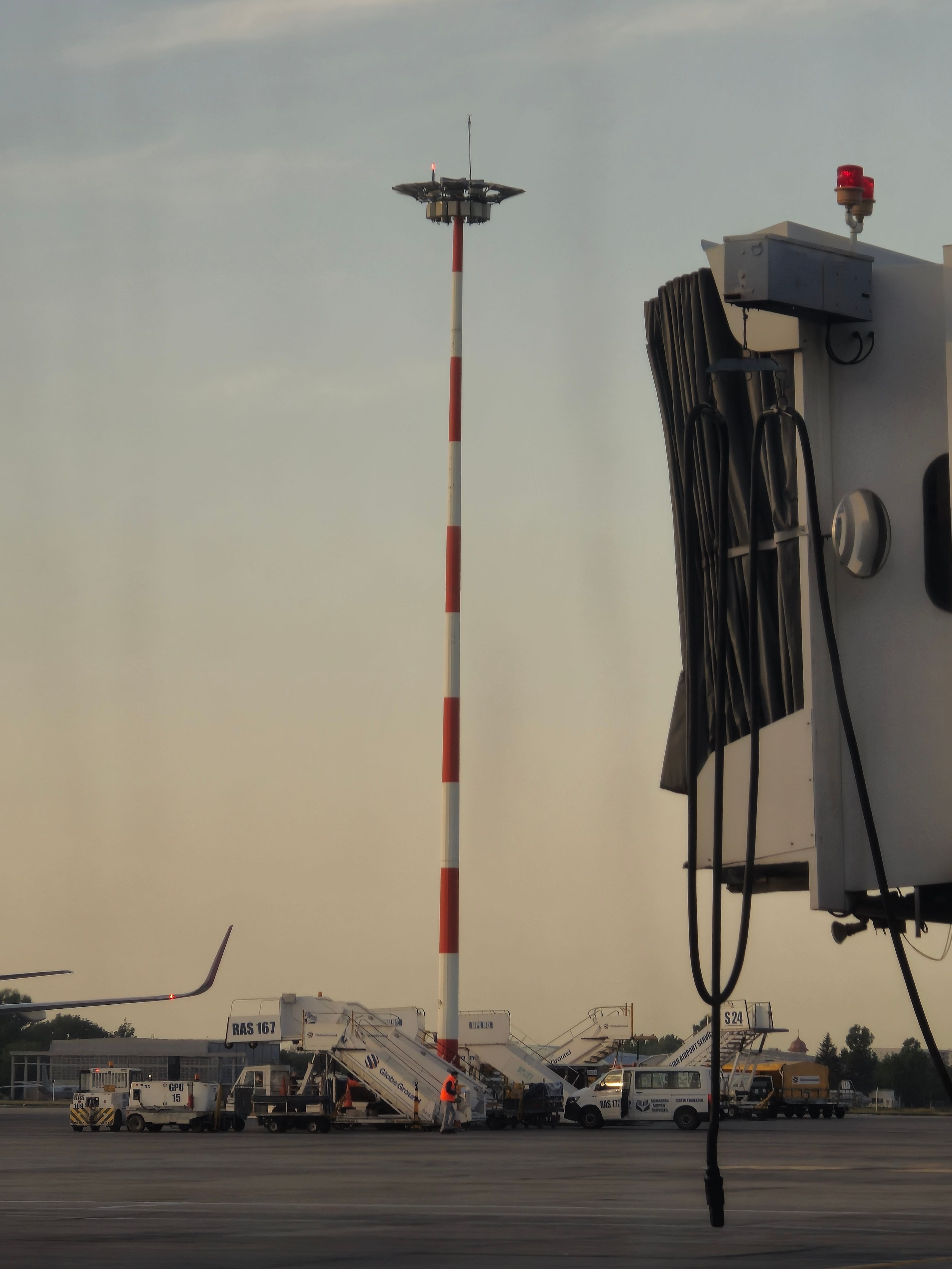 Airport ground view at twilight, featuring boarding stairs and airport equipment.