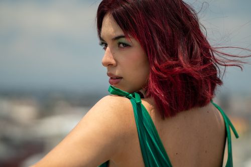 Free Striking outdoor portrait of a redhead woman wearing a green dress, capturing elegance and style. Stock Photo