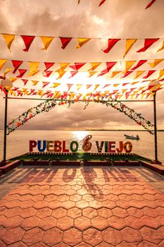 Scenic view of Pueblo Viejo's coastal area at sunset with colorful flags and waterscape.