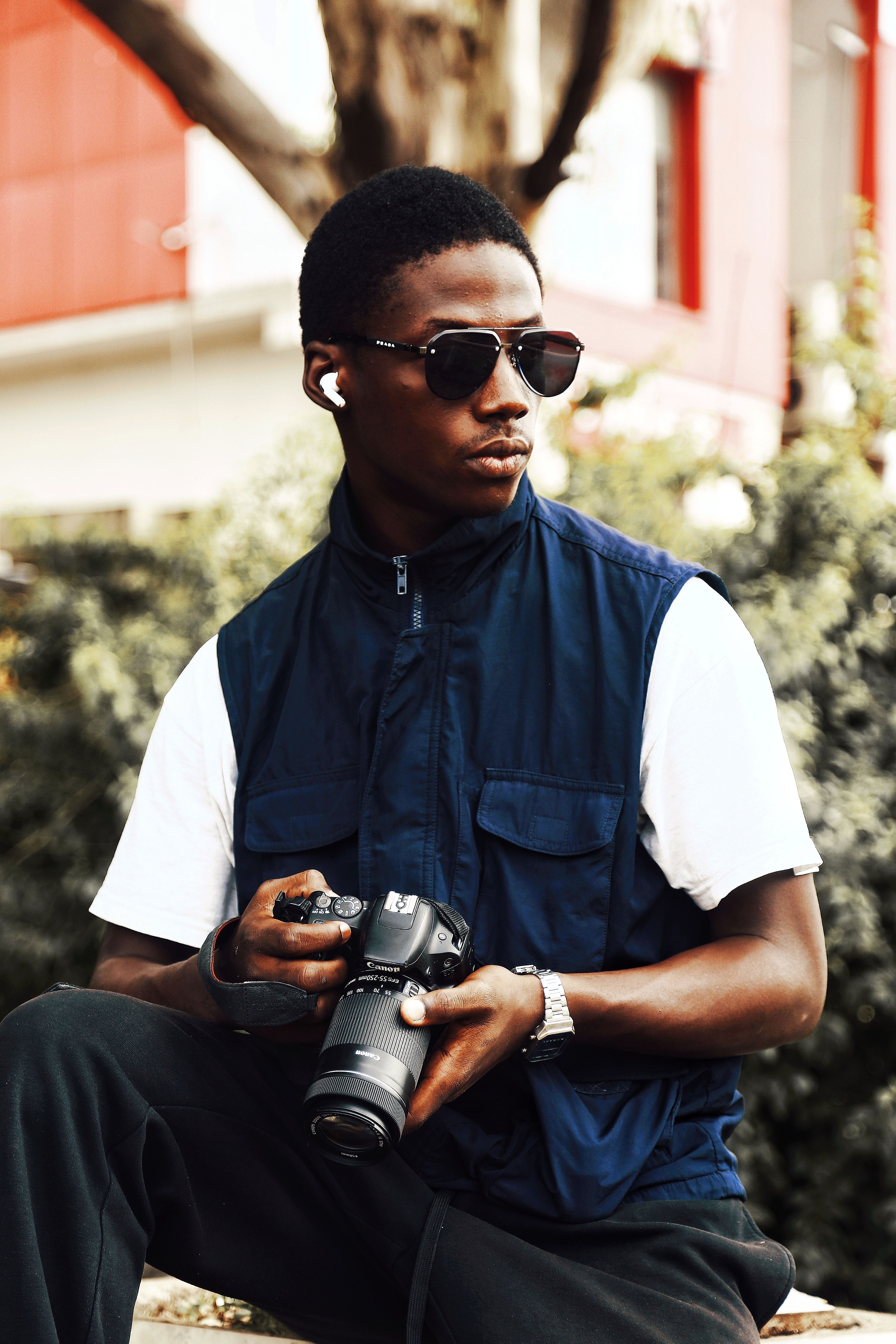 Casual portrait of a young man holding a camera outdoors in Abuja, Nigeria.