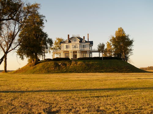 Photo of White and Gray House Near Green Field Surrounded With Trees