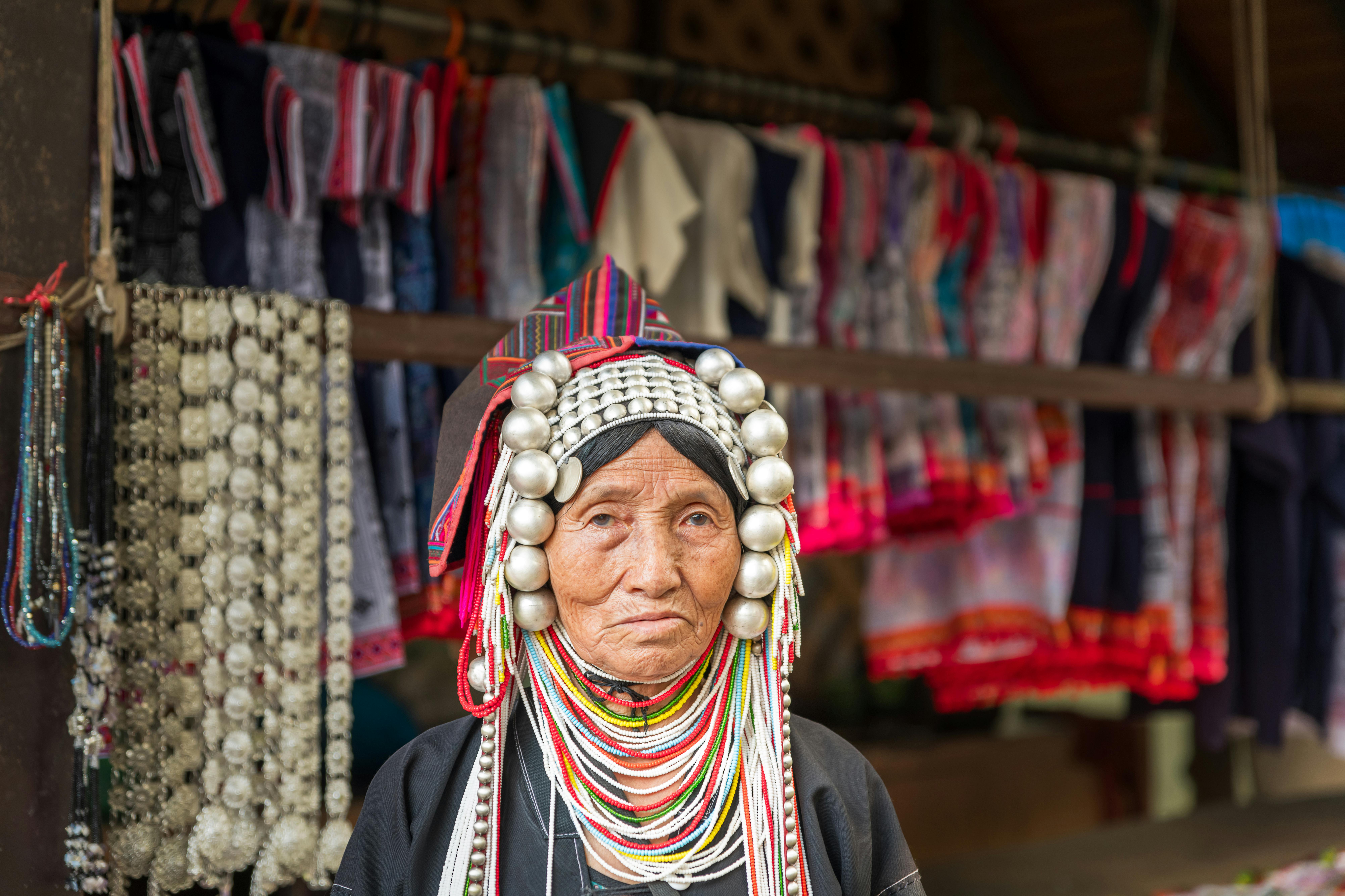Elderly Akha woman in traditional attire at a market in Chiang Rai, Thailand.