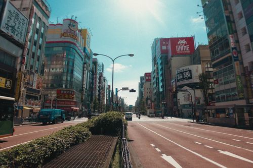 Free Vibrant daytime view of a busy street in Shinjuku, Tokyo. Tall buildings and vibrant signage line the street. Stock Photo