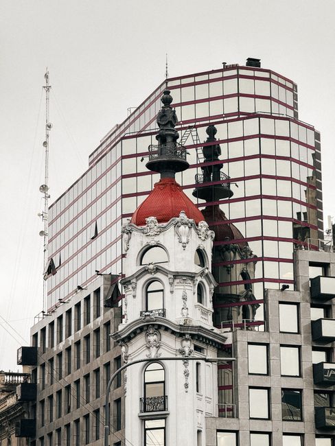 Blend of classic and modern architecture in Buenos Aires, showcasing a historic tower and a mirrored building.
