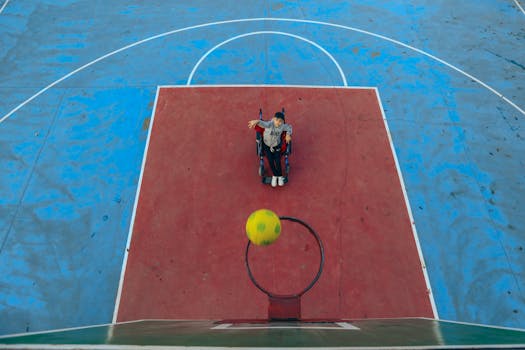 Aerial view of a person in a wheelchair playing basketball on an outdoor court.