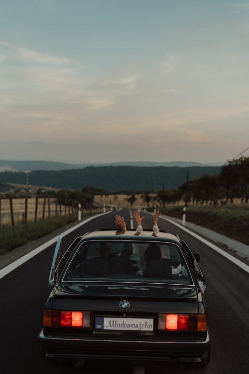 Free Classic BMW E30 driving on an open road with hands raised during sunset. Stock Photo