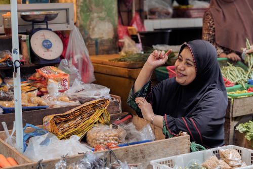 Free A smiling vendor in a hijab at a bustling market in Pontianak, Indonesia. Stock Photo