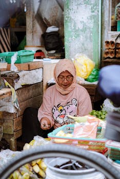 Woman vendor in traditional market in Pontianak, Indonesia, selling fresh vegetables.