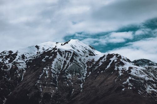 Free Scenic view of a snowcapped mountain peak under an overcast sky. Stock Photo