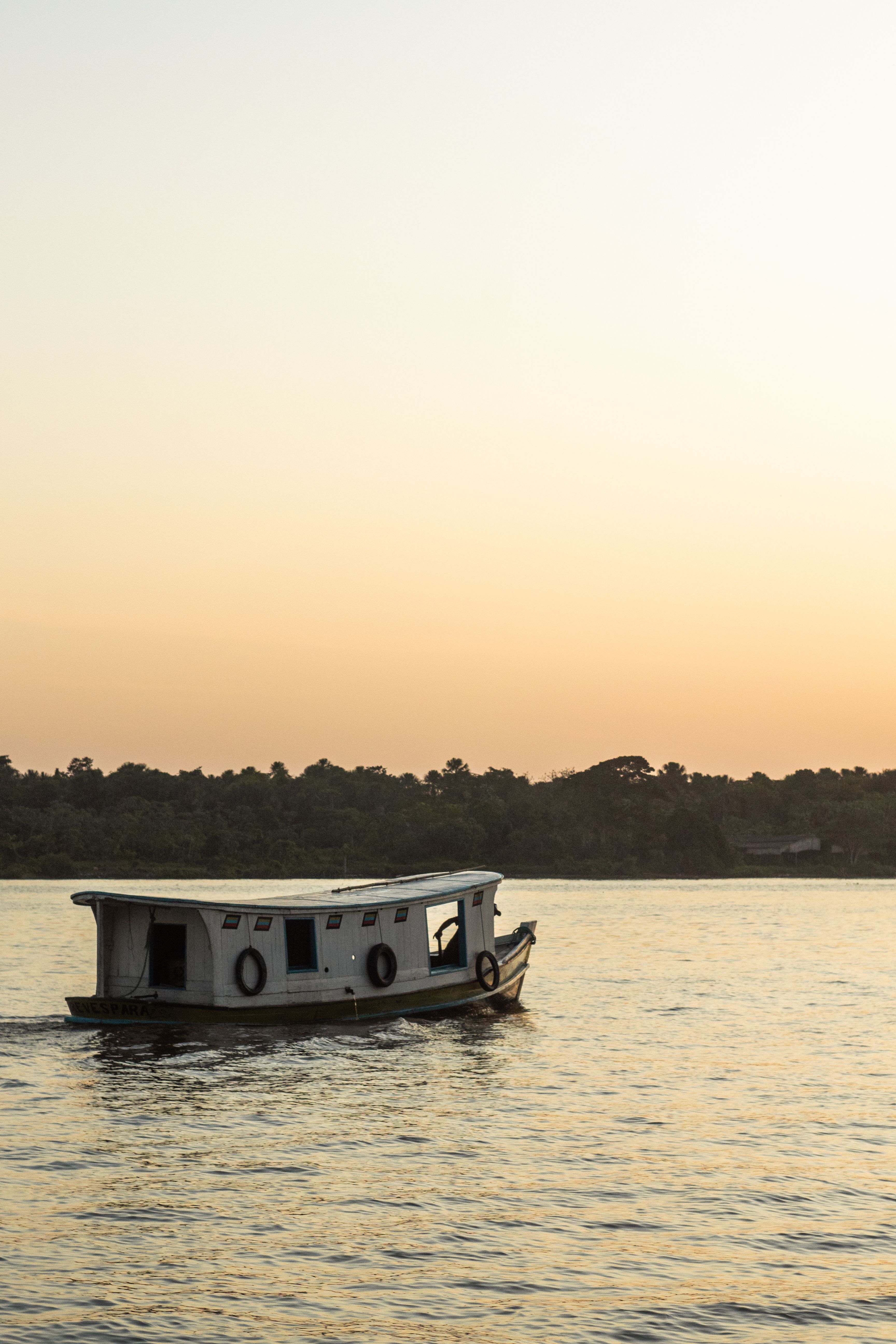A Boat Sailing on a Body of Water at Sunset · Free Stock Photo