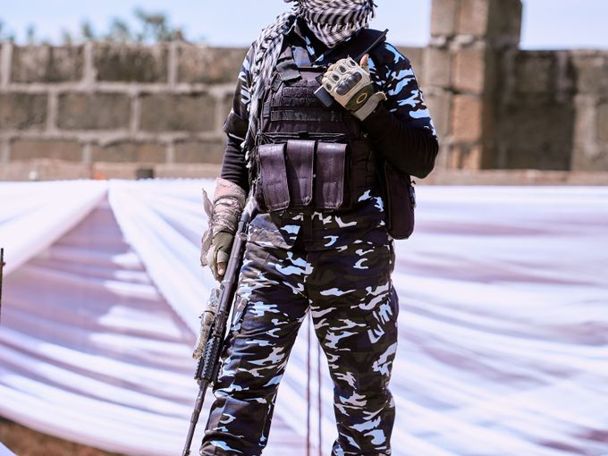 Security response officer in tactical gear standing ready outside a compound