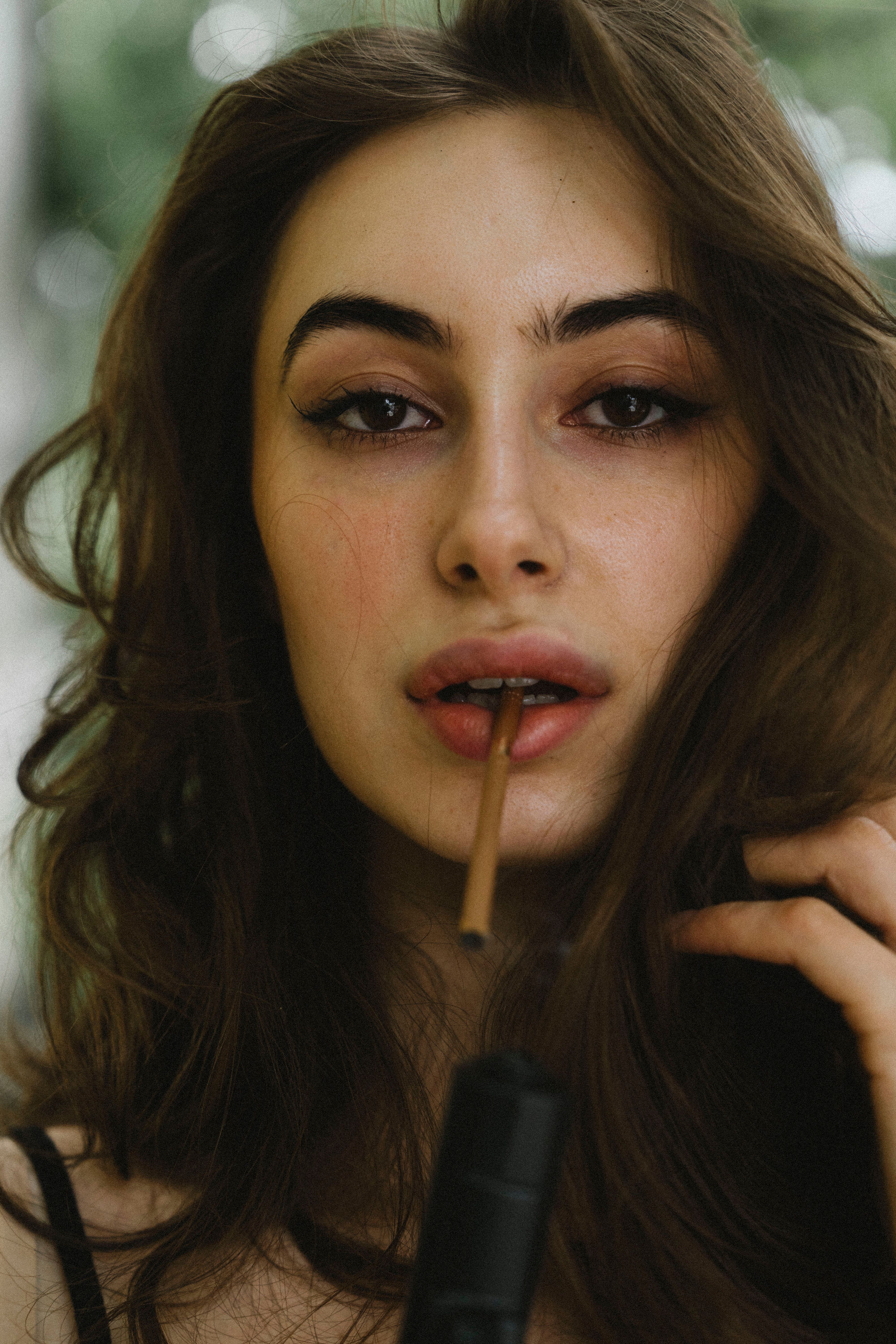 Close-up portrait featuring a woman with smoky eyes and long hair outdoors.