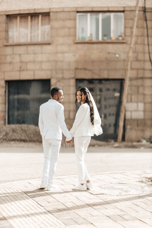 Free A couple in white wedding attire holding hands on a city street in Addis Ababa. Stock Photo