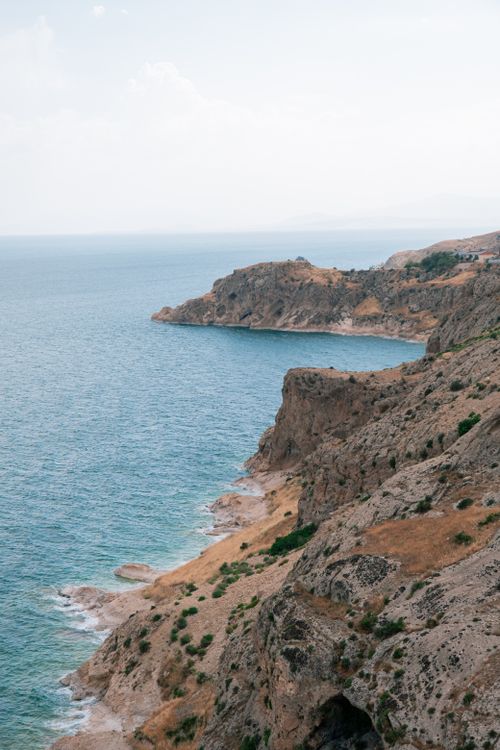 Free Dramatic view of rocky cliffs meeting the serene ocean under a clear sky, perfect for travel inspirations. Stock Photo