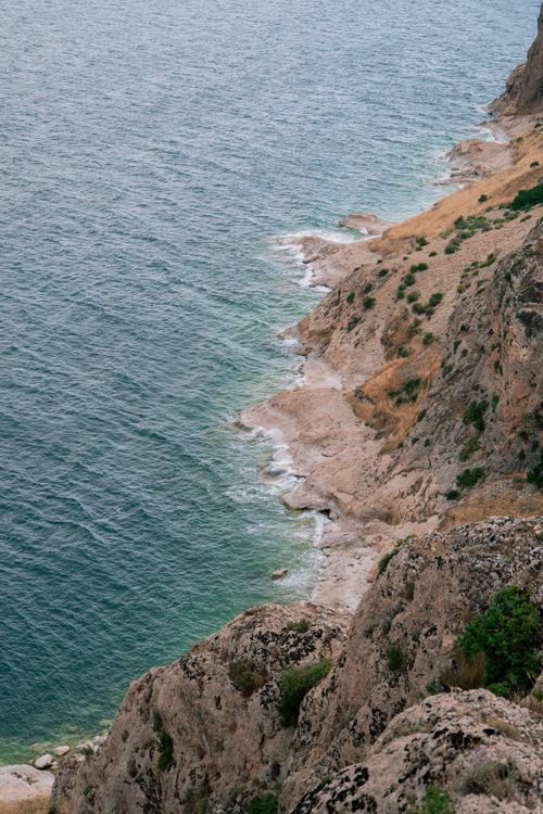Free High angle view of a rugged coastal cliff meeting the blue ocean, capturing nature's beauty. Stock Photo