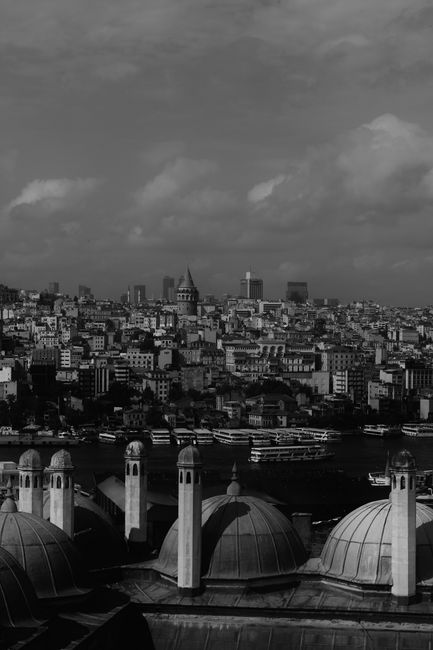 Dramatic black and white skyline of Istanbul featuring the historic Galata Tower under cloudy skies.