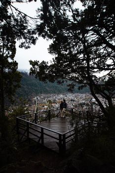Couple embraces on a scenic wooden terrace overlooking San Martín de Los Andes, Argentina.