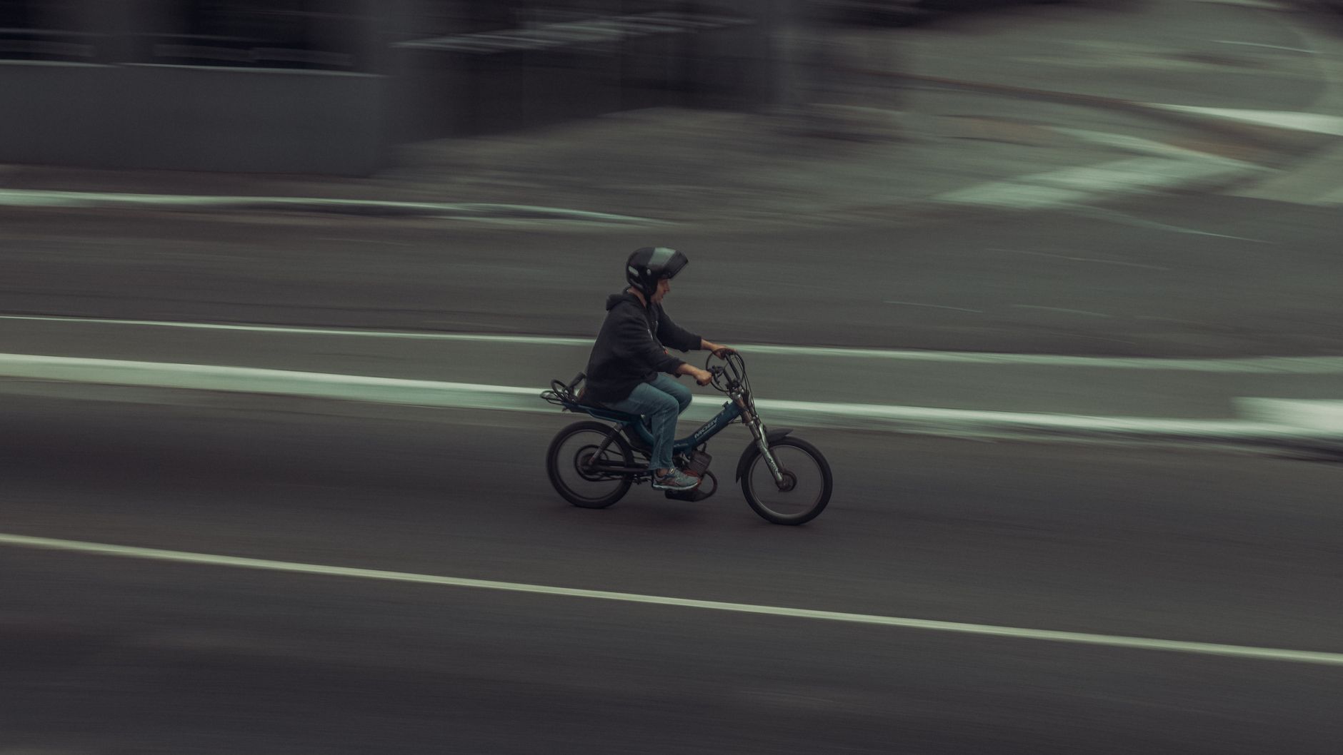 A person riding a bicycle at high speed on a city street, captured with motion blur effect.
