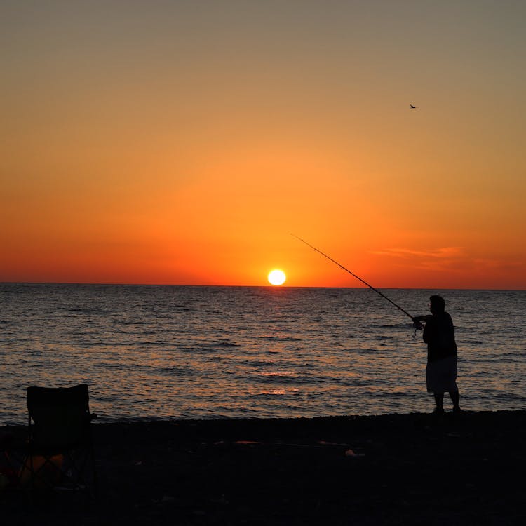 Fisherman On Seashore At Sunset