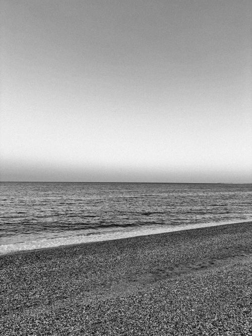 Free Tranquil black and white beach view capturing the calm sea and sky. Stock Photo