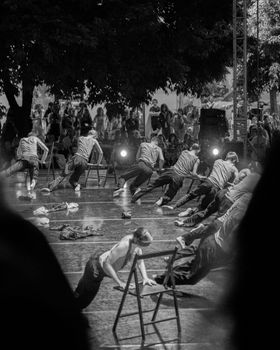 Energetic dancers perform a thrilling act on an outdoor stage with chairs.