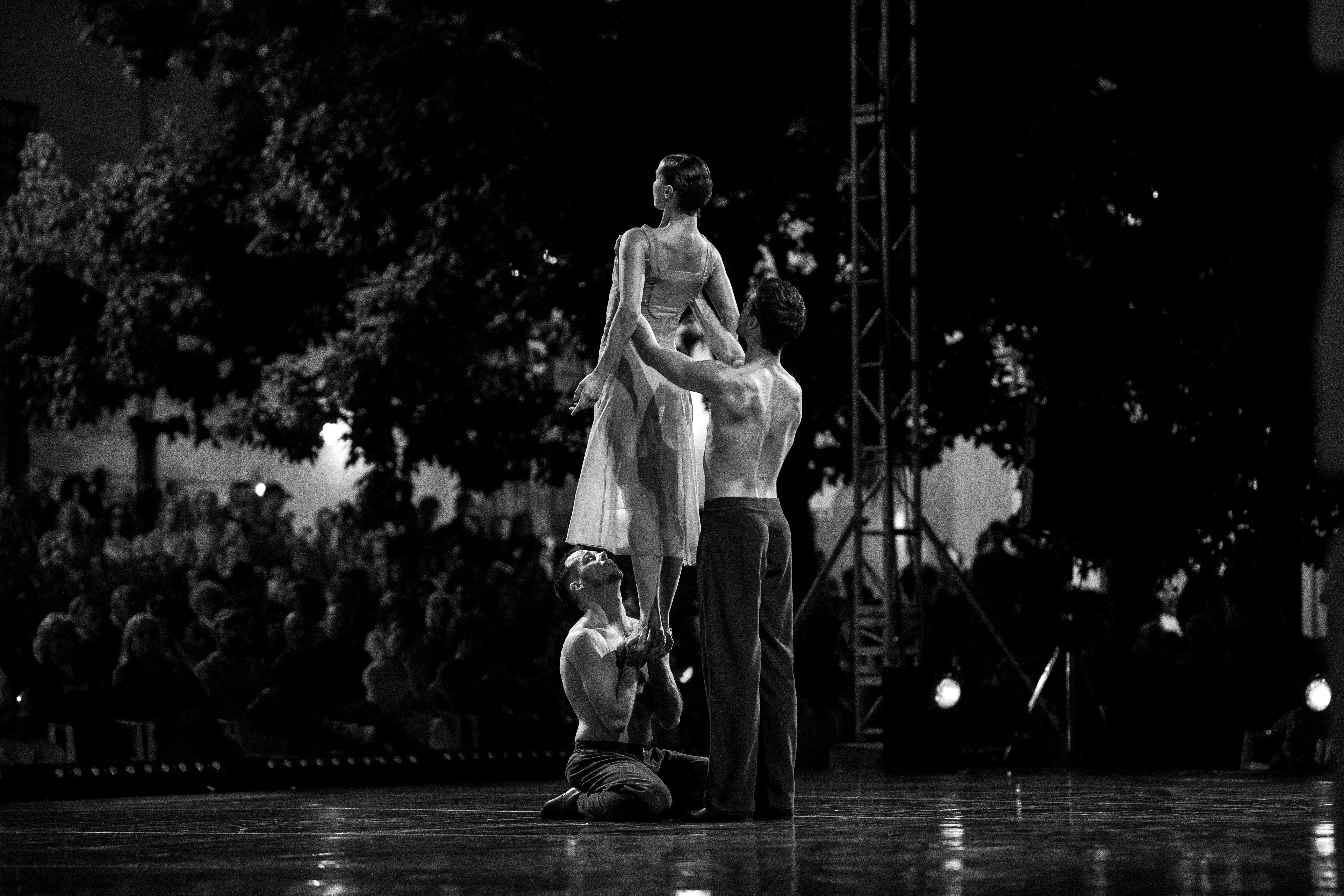 Elegant black and white photo of dancers performing on stage with audience.