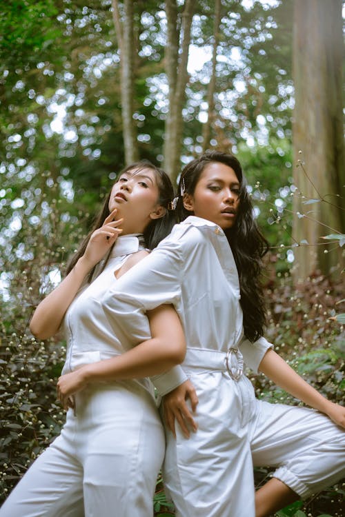 Two Women Standing Beside Each Other Wearing White Top and Bottoms