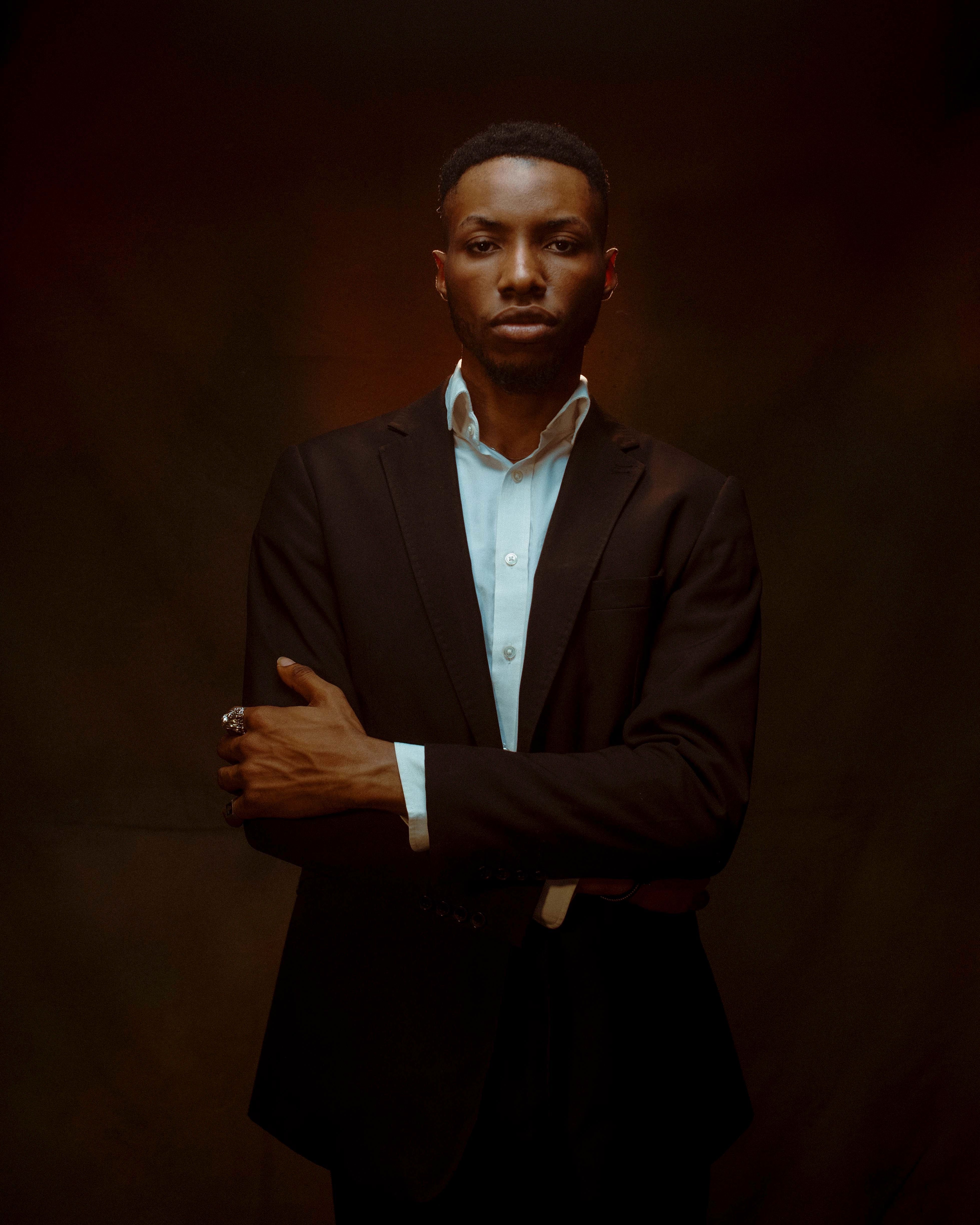 Stylish portrait of a black man in a black suit posing confidently in a studio.