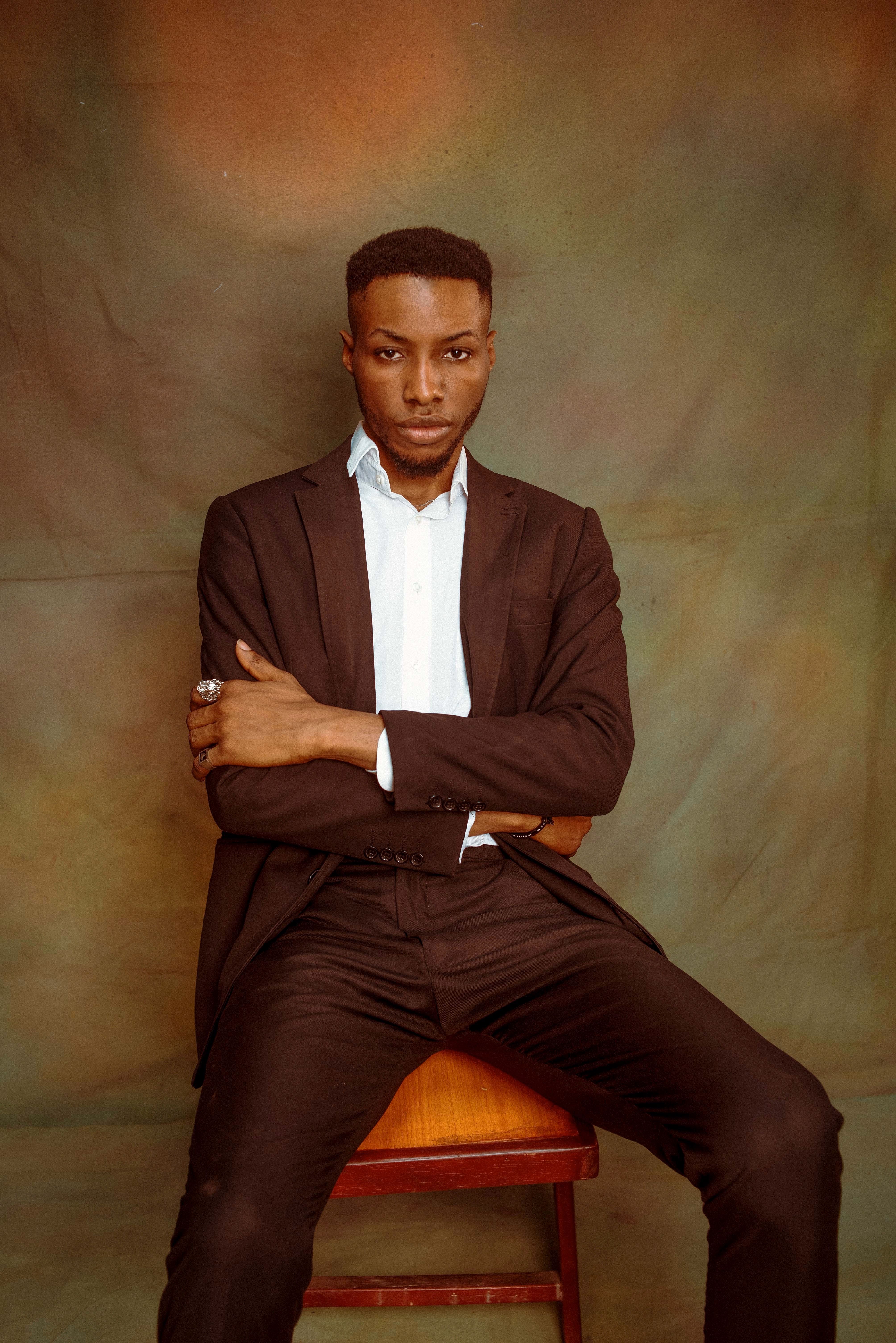 Urban fashion portrait of a confident man in a black suit with crossed arms.