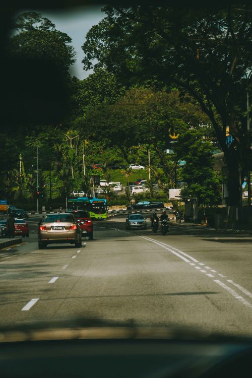Free Dynamic street view in Kuala Lumpur showcasing cars, buses, and lush trees. Stock Photo