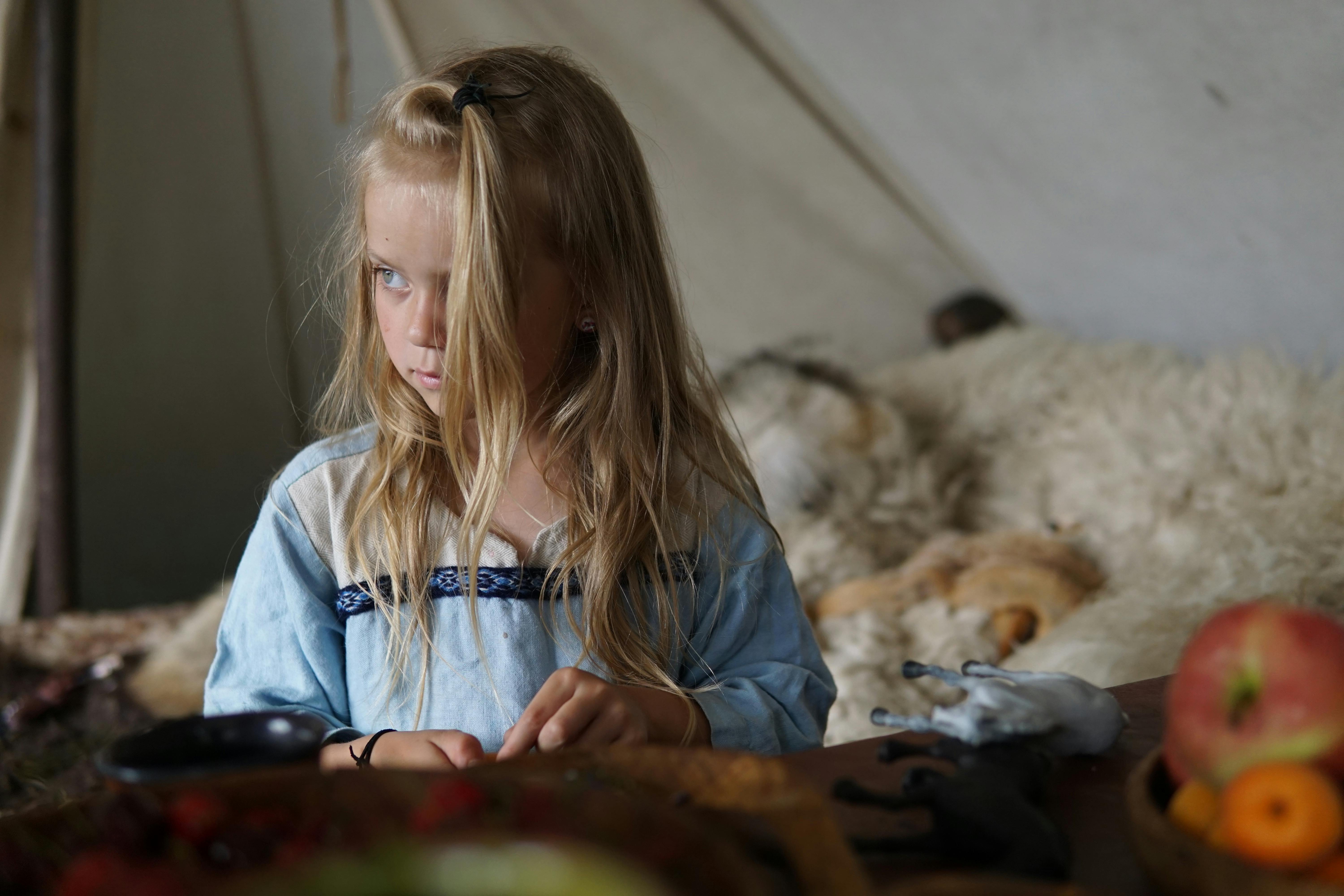 a little girl sitting in front of a tent with fruit