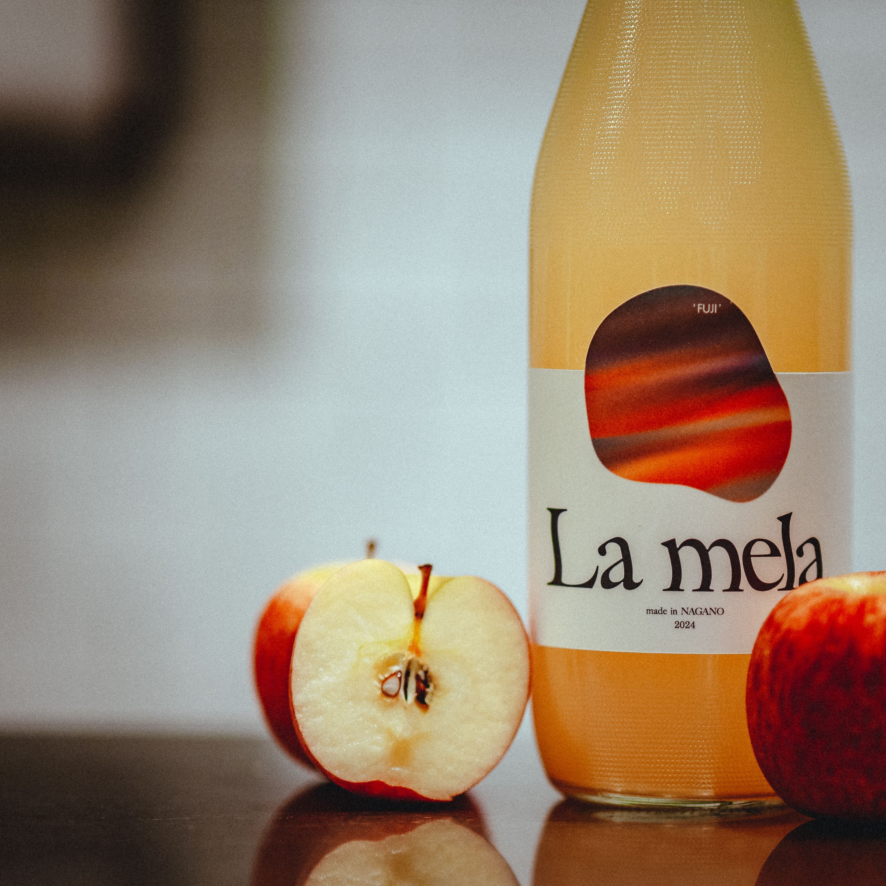 Close-up of a La Mela Fuji apple juice bottle with fresh apples. Perfect for food and drink concepts.