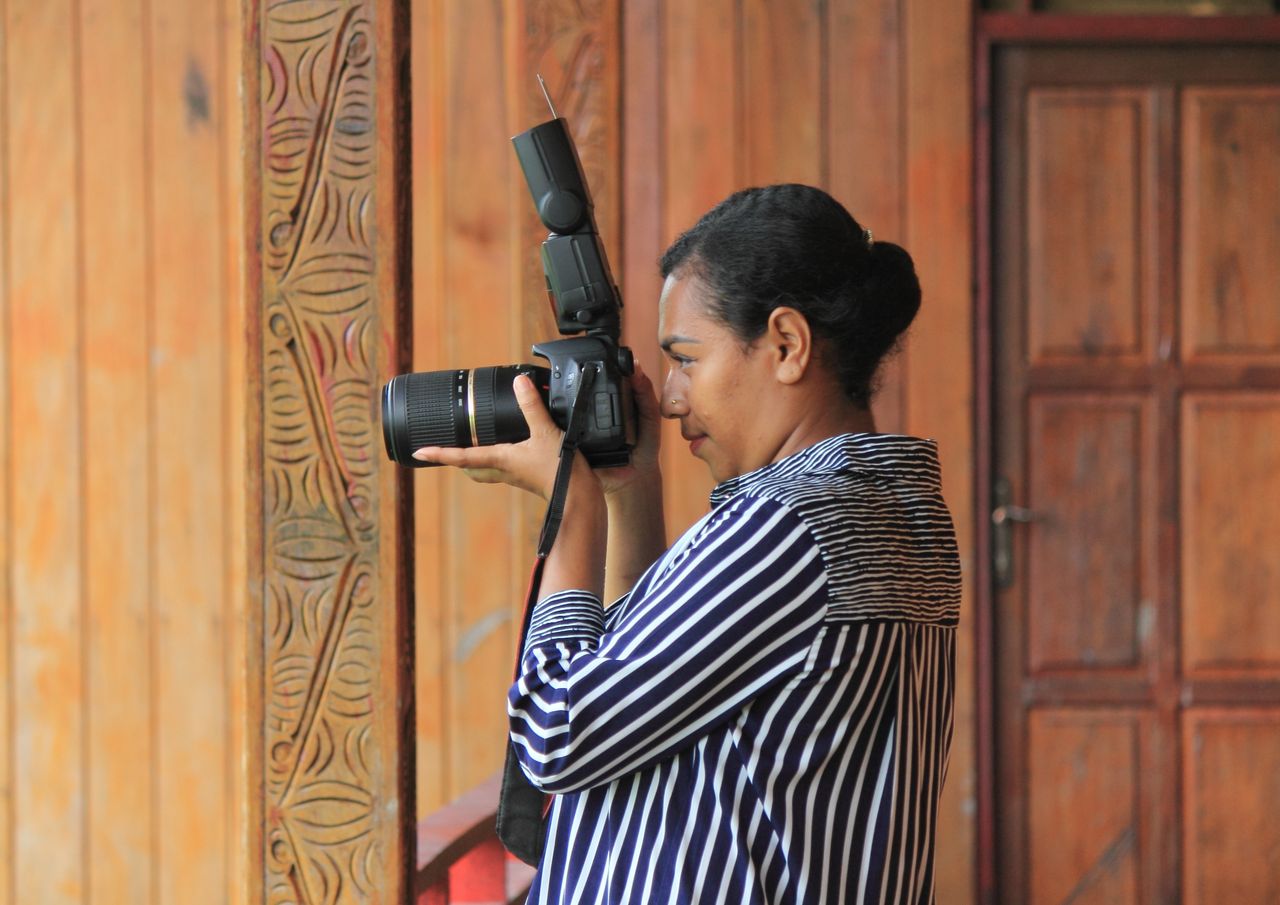 a woman photographer takes a shot indoors in agats papua