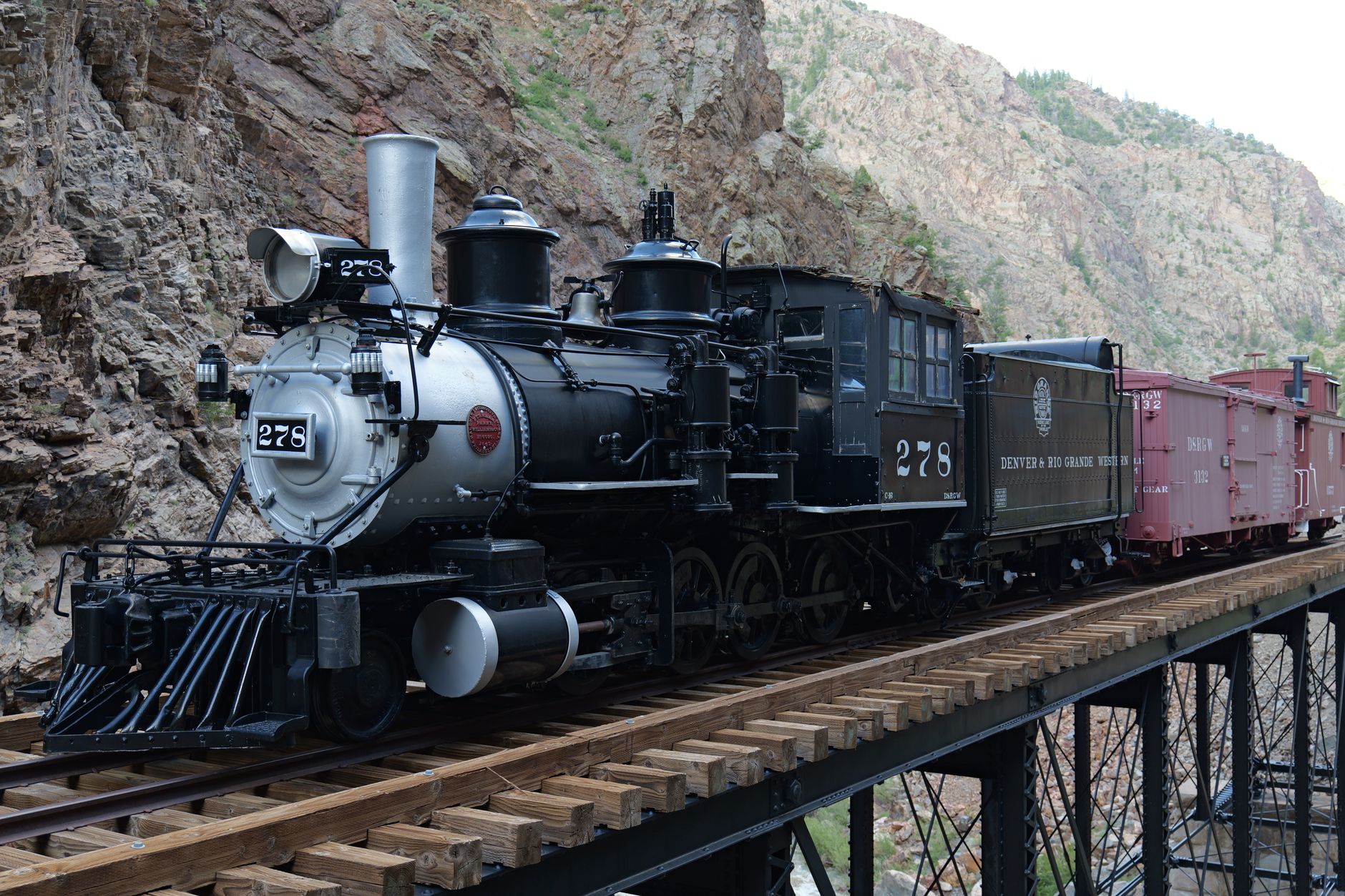 Steam locomotive crossing a mountain bridge with dramatic canyon views
