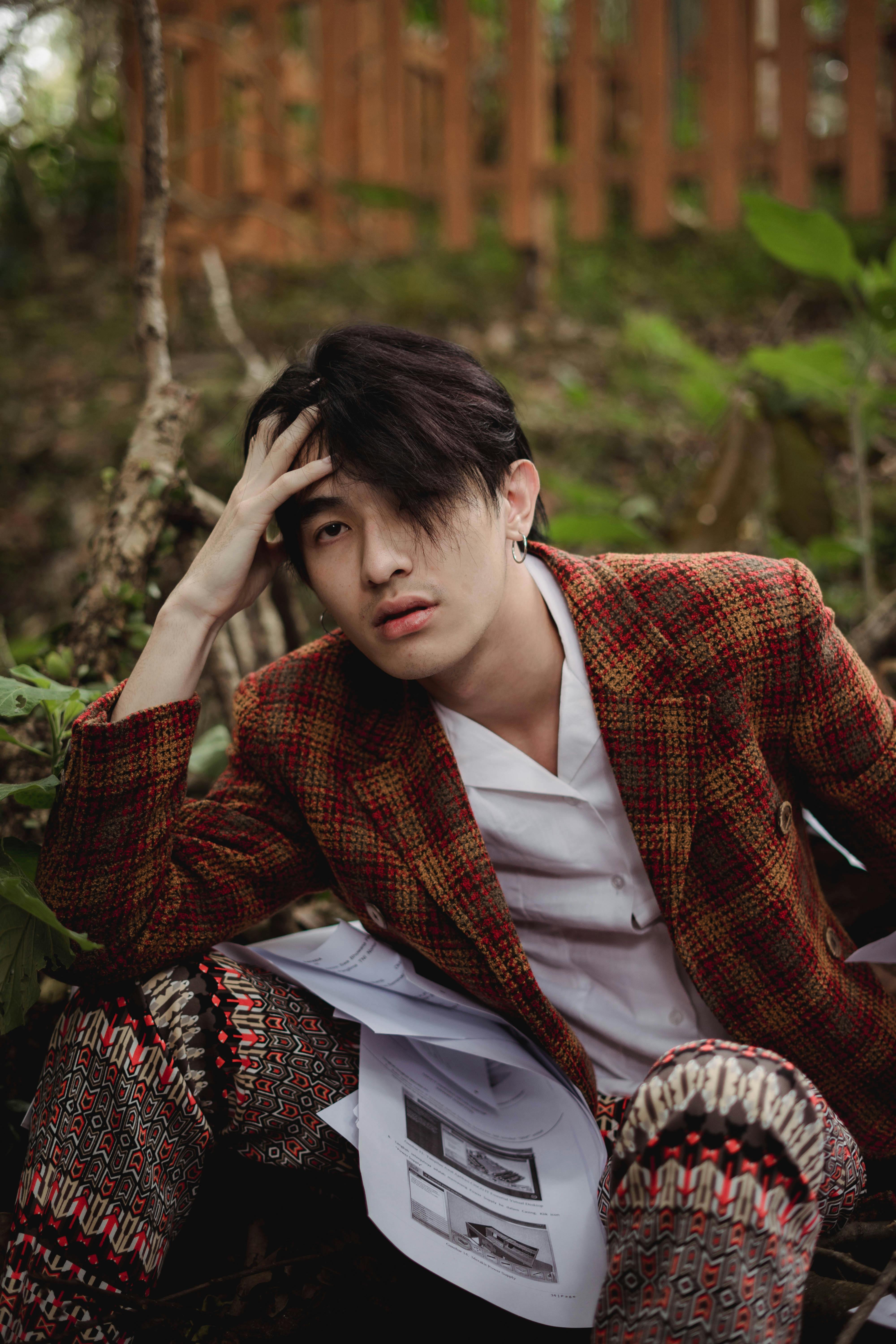 一位时尚男模特身着时装在户外摆拍，神情若有所思