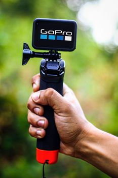 Close-up of a hand gripping a GoPro camera with stabilizer outdoors, showcasing technology use.
