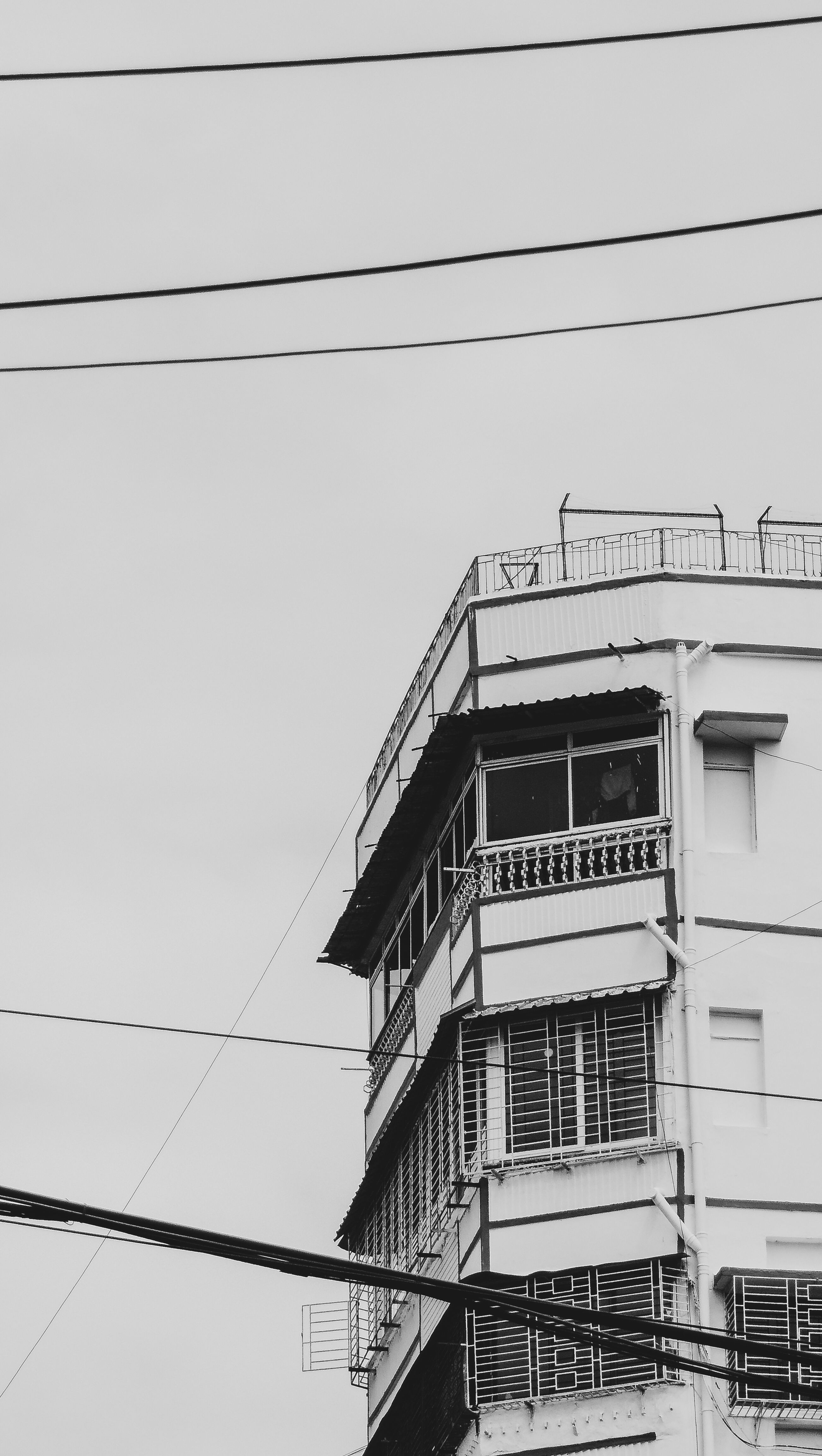 Black and white shot of an urban residential building with power lines.