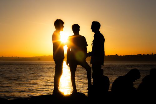 Free Three friends silhouetted against a vibrant Istanbul sunset by the sea. Stock Photo