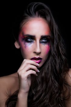 Striking portrait of a woman with bold, colorful makeup and dramatic lighting.