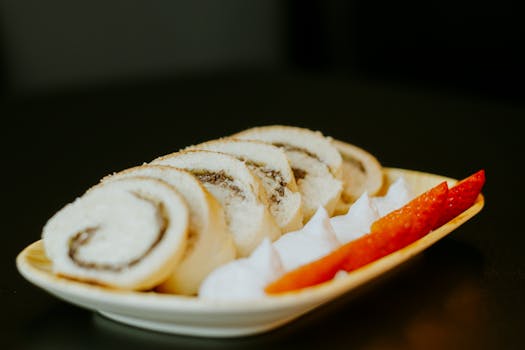 Indulgent Swiss roll slices with fresh strawberries and cream on a stylish plate.
