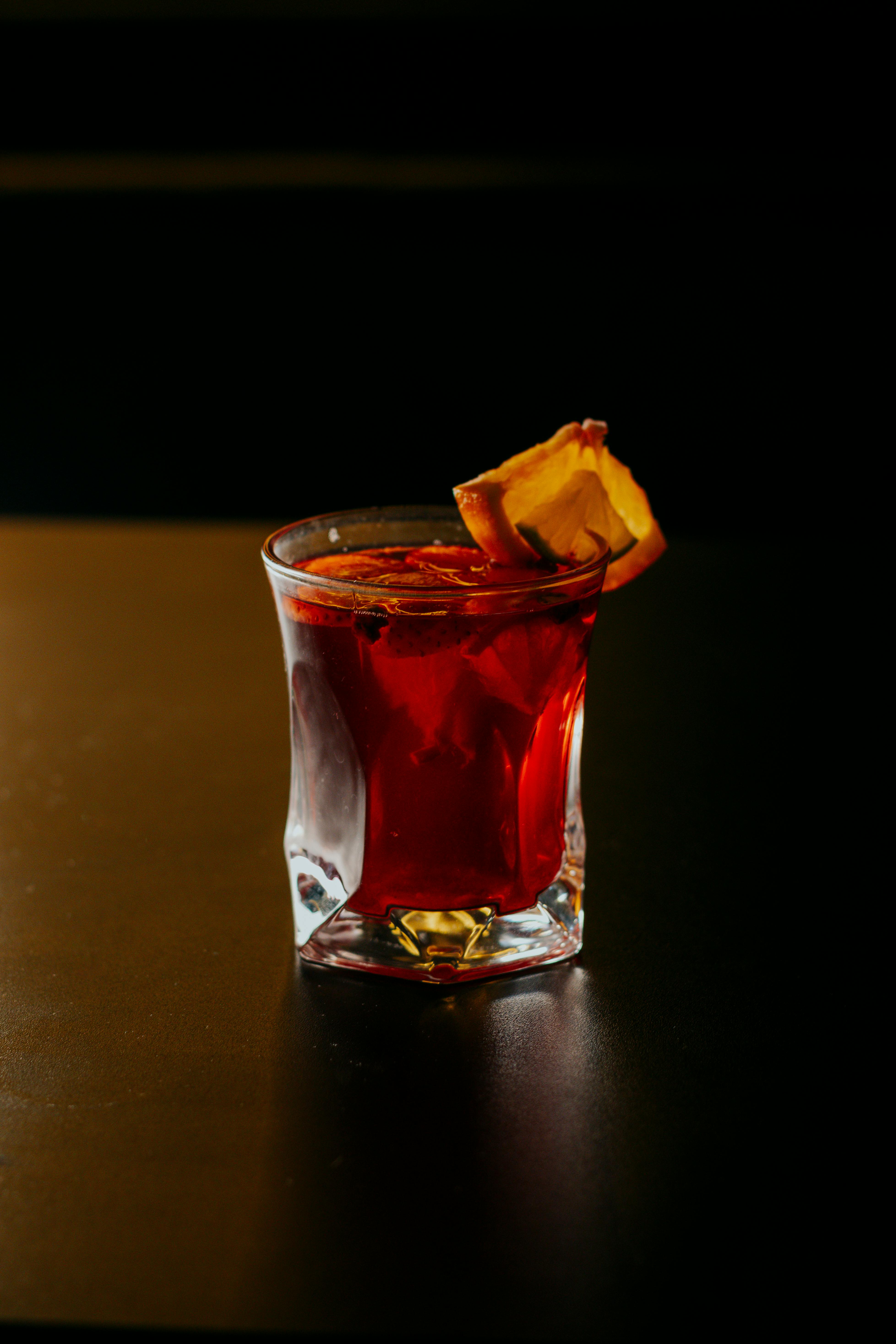 A sophisticated red cocktail garnished with an orange slice, perfect for upscale events.