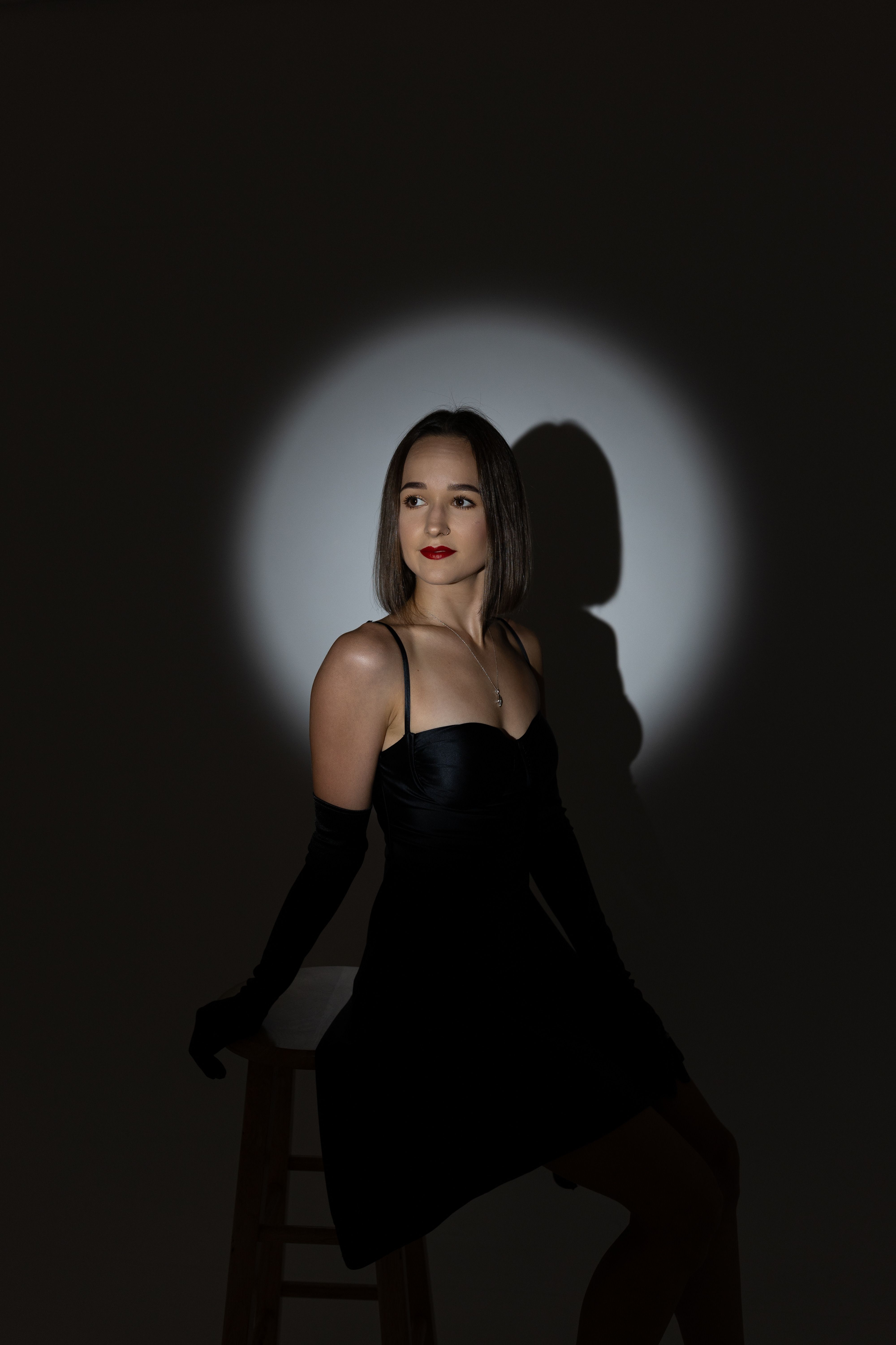 A woman in a black dress sitting on a stool · Free Stock Photo