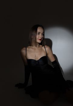 Glamorous portrait of a woman in a black dress highlighting elegance in a studio setting.
