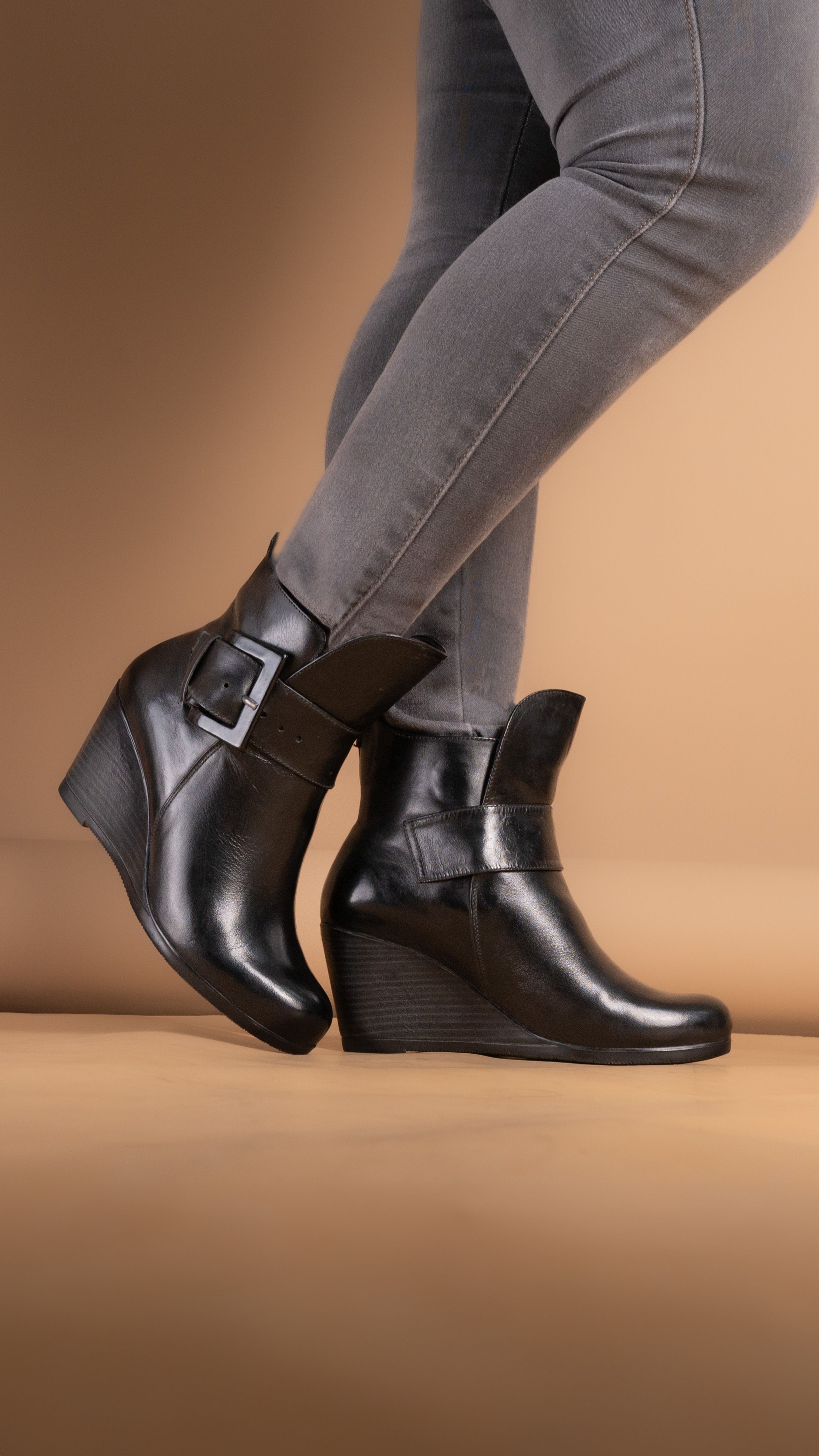 Close-up de botas de couro pretas com salto em wedge combinadas com calças cinzas, perfeitas para uma moda chique.